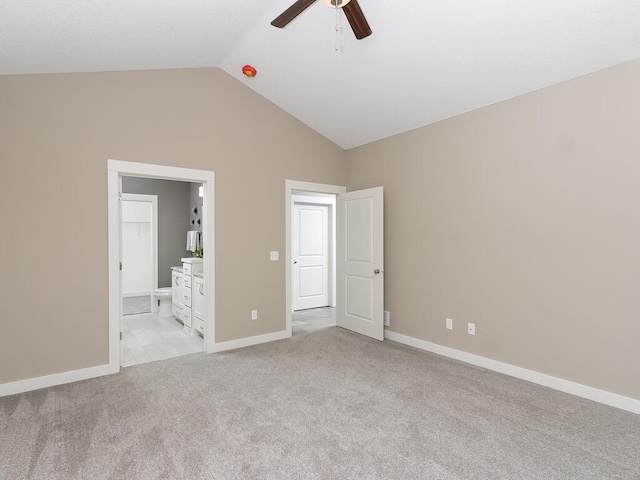 unfurnished bedroom with light colored carpet, ensuite bath, ceiling fan, and lofted ceiling