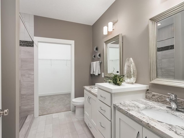 bathroom featuring vanity, toilet, and tiled shower