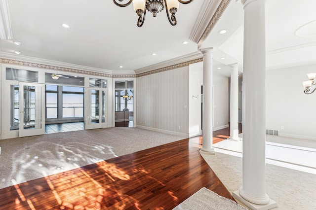 carpeted living room with crown molding, a chandelier, decorative columns, and french doors