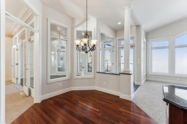 unfurnished dining area with an inviting chandelier, dark wood-type flooring, and decorative columns