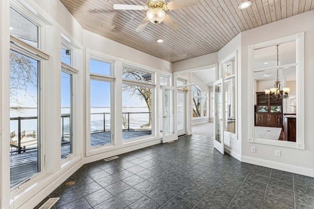 unfurnished sunroom with ceiling fan with notable chandelier, a wealth of natural light, and wooden ceiling