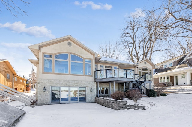 snow covered property with french doors and a deck