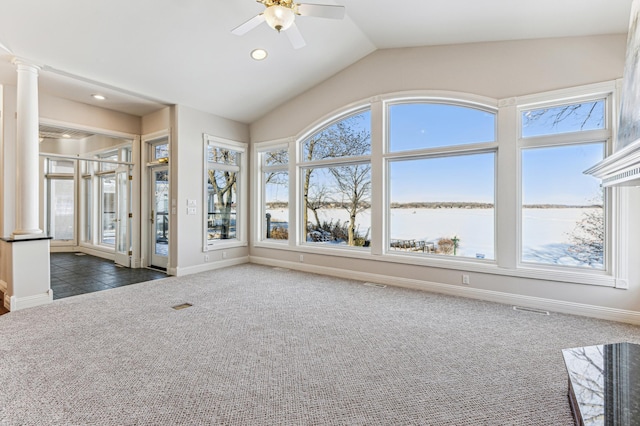 unfurnished living room with lofted ceiling, ornate columns, a water view, dark carpet, and baseboards