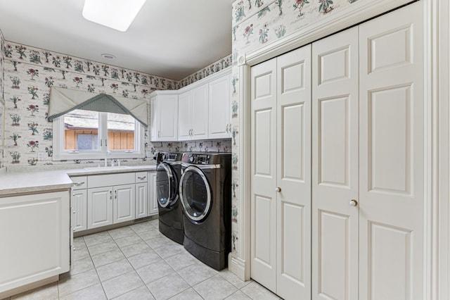 laundry room with wallpapered walls, light tile patterned floors, cabinet space, washing machine and dryer, and a sink