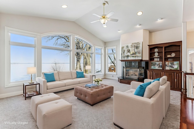 living area featuring lofted ceiling, recessed lighting, a ceiling fan, baseboards, and a glass covered fireplace