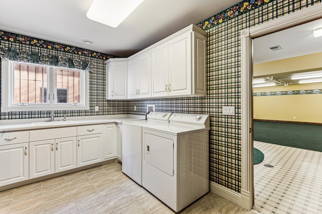 washroom featuring cabinet space, baseboards, visible vents, washer and clothes dryer, and a sink