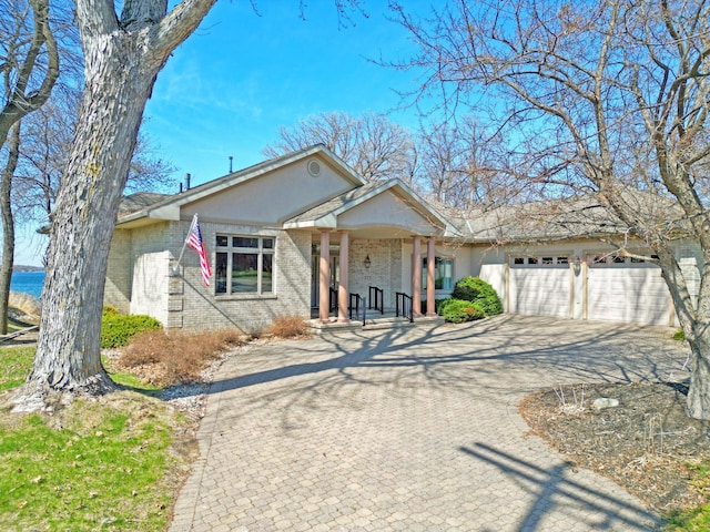 single story home with a garage, stucco siding, driveway, and brick siding