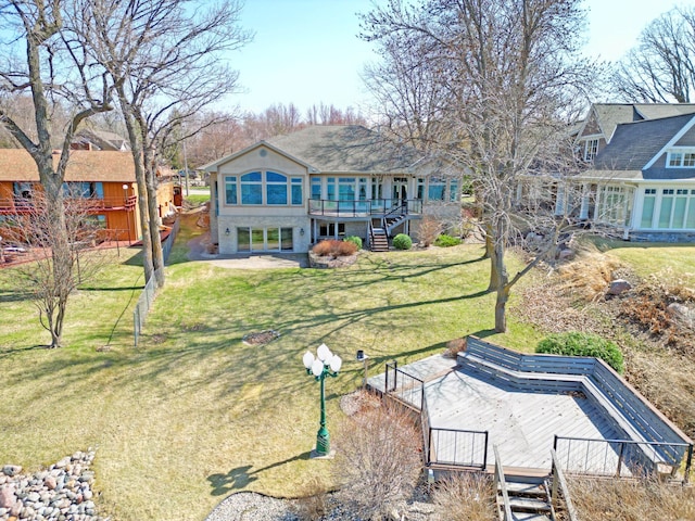 rear view of house featuring stairway, a lawn, and a deck