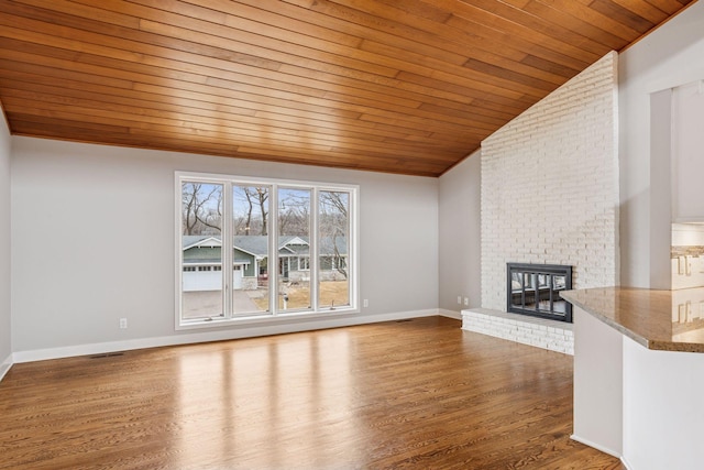 unfurnished living room with baseboards, vaulted ceiling, a fireplace, wooden ceiling, and wood finished floors