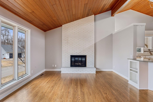 unfurnished living room with wood ceiling, lofted ceiling, a brick fireplace, and wood finished floors