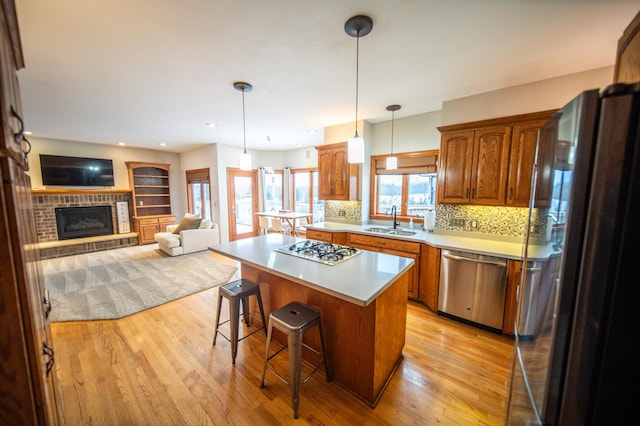 kitchen featuring a kitchen island, sink, a breakfast bar area, stainless steel appliances, and a brick fireplace