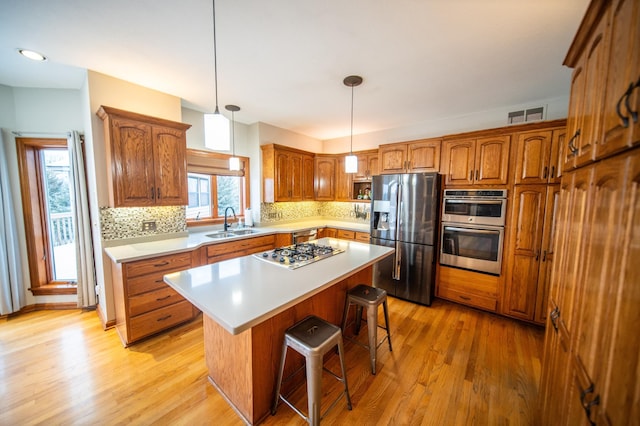 kitchen with stainless steel appliances, a kitchen island, sink, and light wood-type flooring