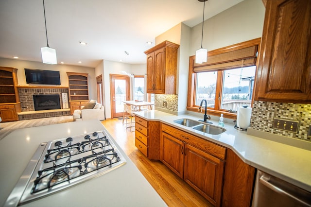 kitchen featuring decorative light fixtures, sink, a brick fireplace, and gas stovetop