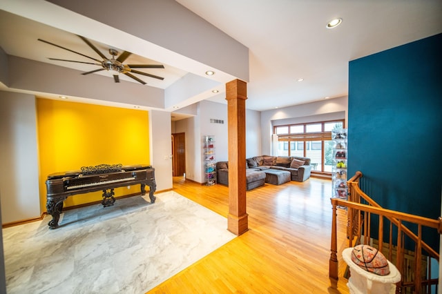 recreation room with hardwood / wood-style flooring, ceiling fan, and ornate columns