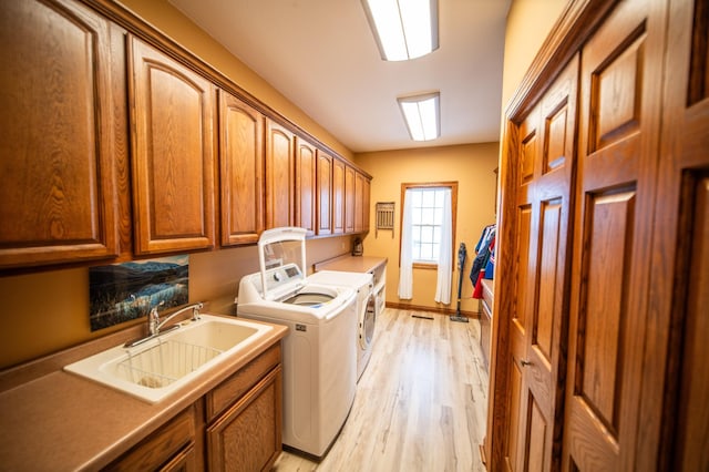 laundry area with cabinets, sink, light hardwood / wood-style floors, and washer and dryer