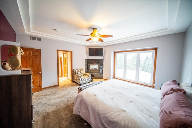 bedroom featuring a multi sided fireplace, light carpet, ceiling fan, and a tray ceiling