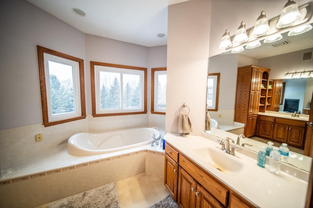 bathroom with tile patterned floors, vanity, and tiled bath