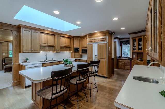 kitchen featuring a center island, light hardwood / wood-style floors, sink, and a skylight