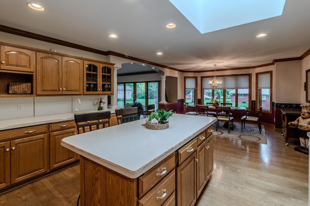 kitchen featuring a wealth of natural light, a kitchen island, hanging light fixtures, and light wood-type flooring