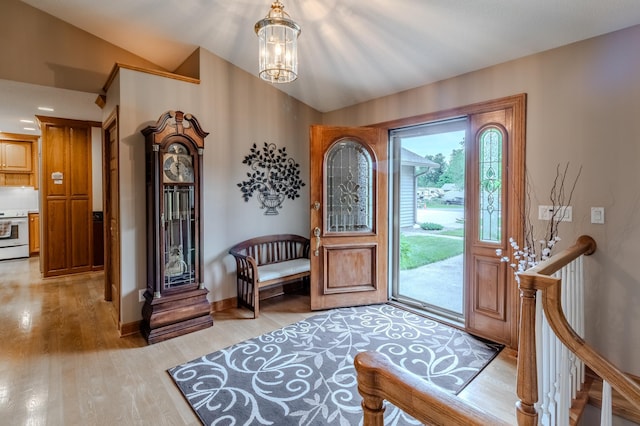 entryway featuring light wood-type flooring, lofted ceiling, and an inviting chandelier