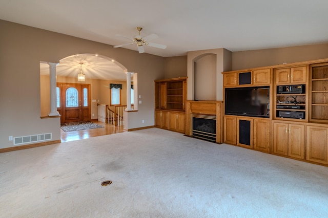 unfurnished living room with ceiling fan, light colored carpet, and ornate columns