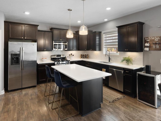 kitchen with dark hardwood / wood-style floors, pendant lighting, sink, a center island, and stainless steel appliances