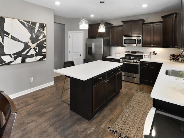 kitchen featuring stainless steel appliances, a center island, a kitchen bar, dark hardwood / wood-style flooring, and decorative light fixtures