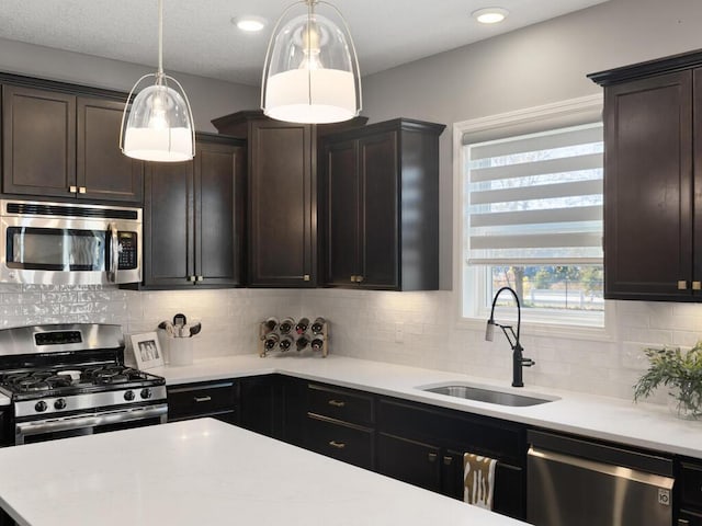 kitchen featuring pendant lighting, sink, stainless steel appliances, and dark brown cabinetry