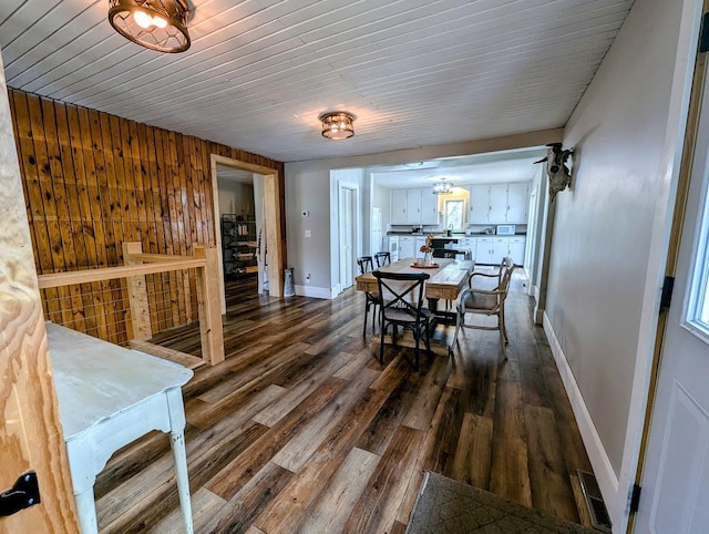 dining room with wood walls, dark wood-type flooring, and wooden ceiling