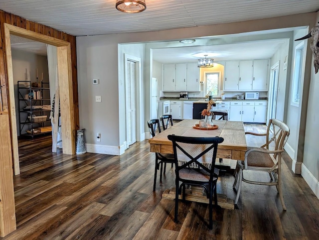 dining room with dark hardwood / wood-style flooring and wood walls