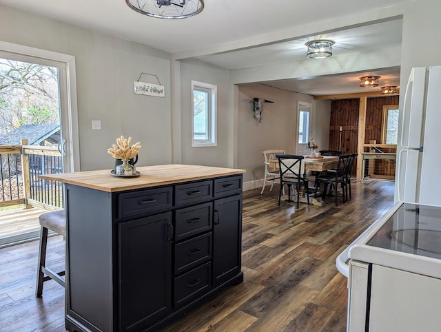 kitchen with a kitchen bar, a wealth of natural light, white fridge, and range