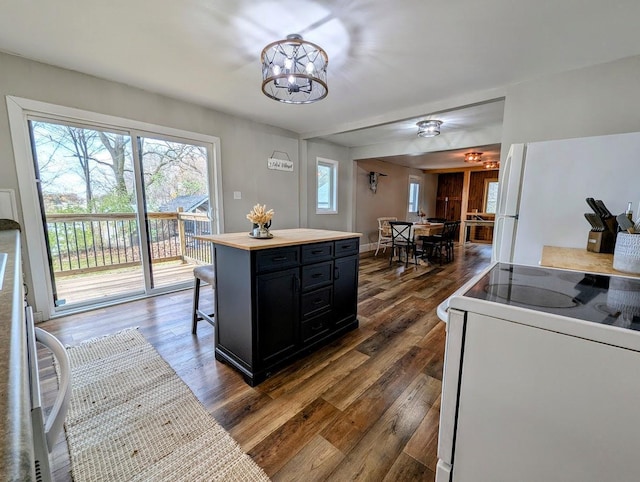 kitchen with a center island, stove, a kitchen breakfast bar, dark hardwood / wood-style floors, and white fridge