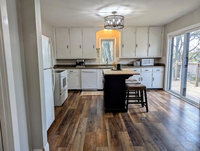 kitchen featuring white cabinetry, a center island, white appliances, and sink