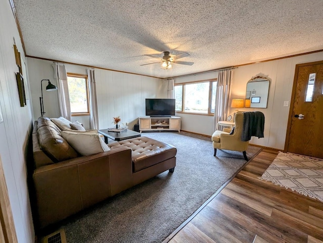 living room with a textured ceiling, hardwood / wood-style flooring, ceiling fan, and crown molding