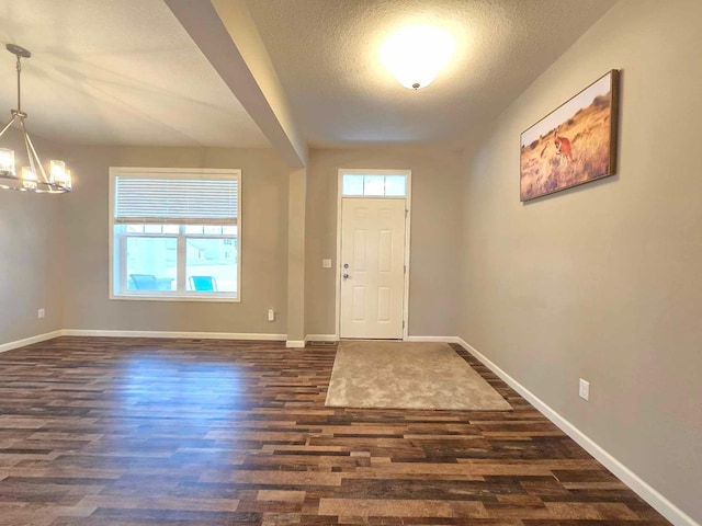 entrance foyer featuring a textured ceiling, dark hardwood / wood-style floors, and an inviting chandelier