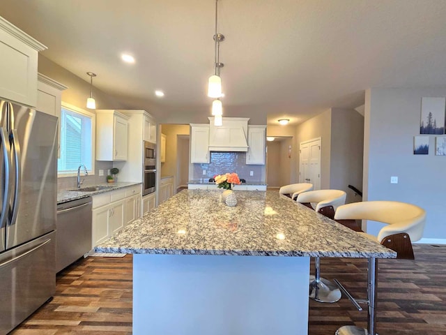 kitchen featuring white cabinets, appliances with stainless steel finishes, a kitchen island, and pendant lighting