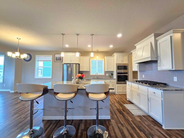 kitchen with white cabinetry, a kitchen island, stainless steel appliances, and decorative light fixtures