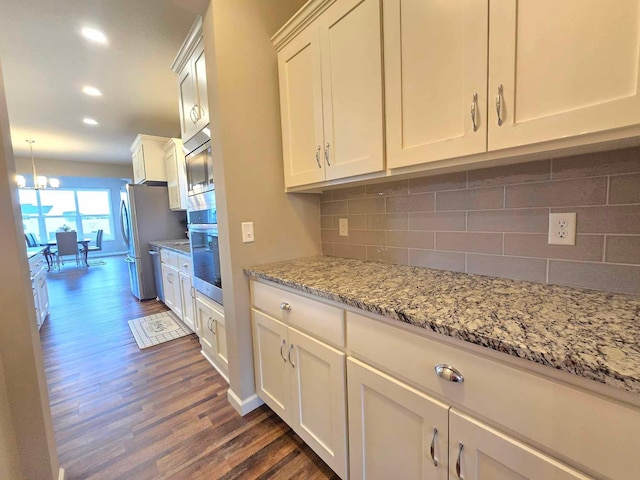 kitchen featuring dark wood-type flooring, backsplash, white cabinets, light stone counters, and stainless steel appliances