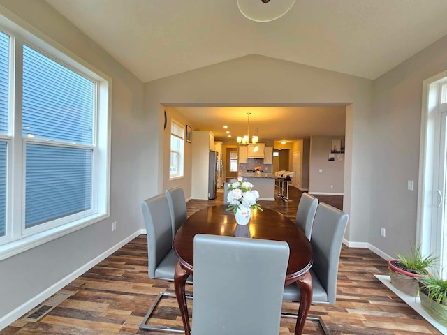 dining space with a chandelier, dark hardwood / wood-style flooring, vaulted ceiling, and plenty of natural light