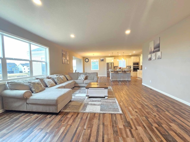 living room featuring plenty of natural light, wood-type flooring, and an inviting chandelier