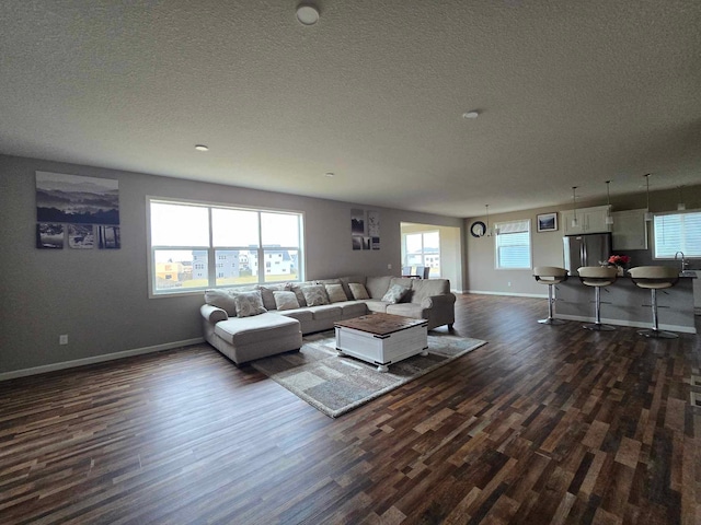 living room with a textured ceiling, dark hardwood / wood-style floors, and a wealth of natural light