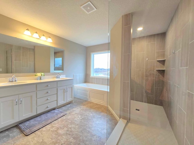 bathroom with a textured ceiling, vanity, and independent shower and bath