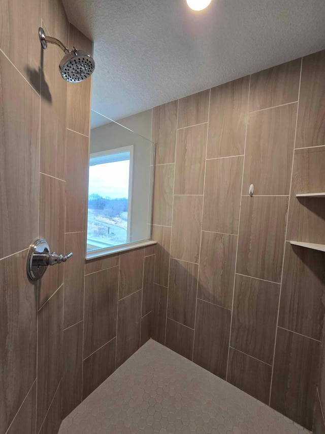 bathroom with tiled shower and a textured ceiling