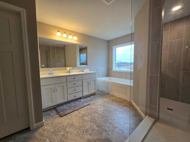 bathroom featuring separate shower and tub, vanity, and a textured ceiling