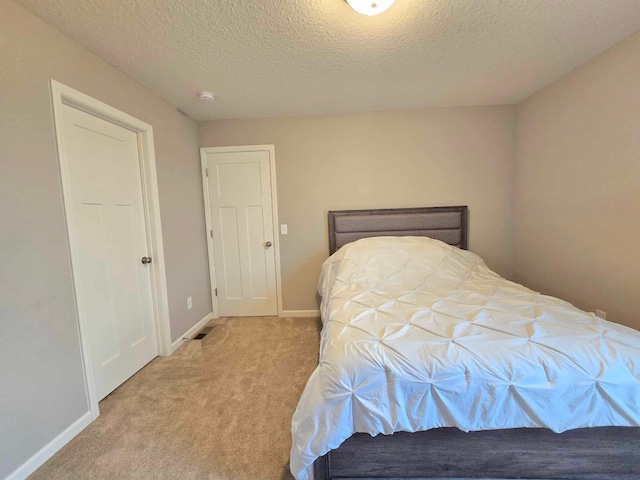 bedroom featuring light colored carpet and a textured ceiling