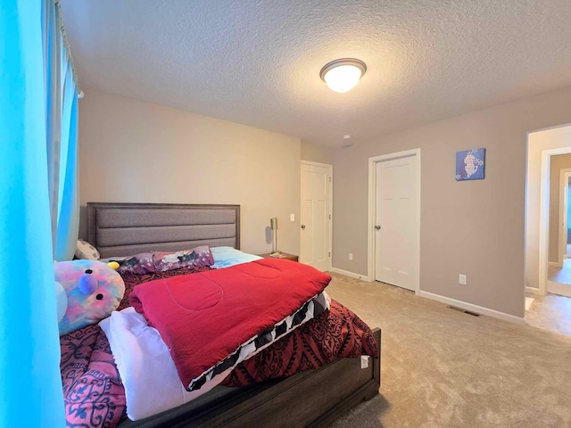 bedroom featuring a textured ceiling and light colored carpet