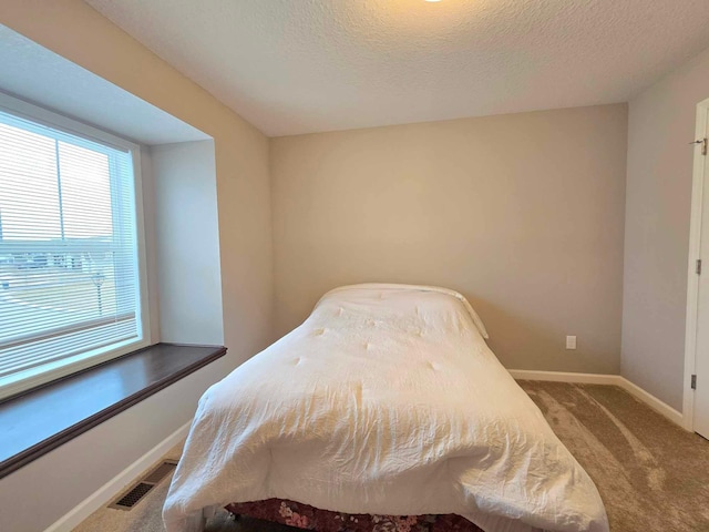 bedroom with light carpet and a textured ceiling