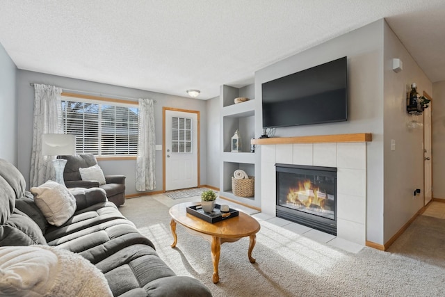 living room featuring a textured ceiling, light colored carpet, a tile fireplace, and built in shelves