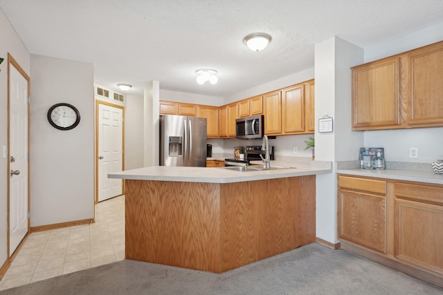 kitchen with a textured ceiling, stainless steel appliances, light carpet, and kitchen peninsula