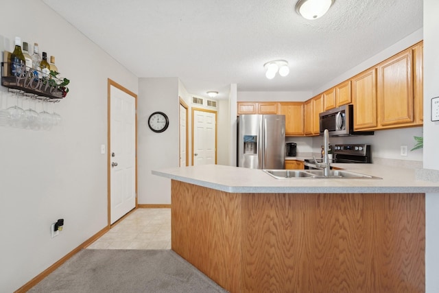 kitchen featuring a textured ceiling, appliances with stainless steel finishes, light carpet, sink, and kitchen peninsula